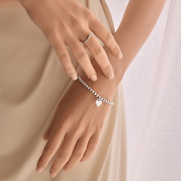 Silverarmband med hjärthängande berlock och matchande v-formad ring.